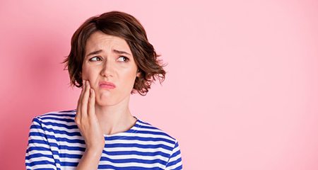 Woman frowning while rubbing her jaw