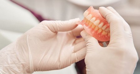 Technician carefully holding a set of dentures