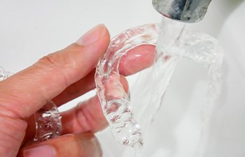 Patient in Gainesville cleaning their Invisalign aligners