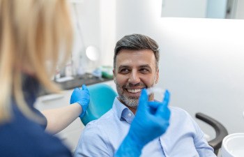 Man smiling at dentist who is holding Invisalign with blue gloves