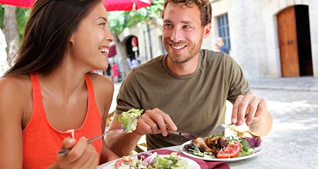 Couple smiling while eating healthy meal outside