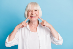 Woman smiling and pointing to her dental implants